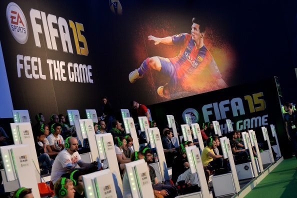 COLOGNE, GERMANY - AUGUST 14:  Visitors try out the game 'FIFA 15' at the EA Sports stand at the 2014 Gamescom gaming trade fair on August 14, 2014 in Cologne, Germany. Gamescom is the world's largest gaming convention and this year includes over 600 exhibitors.  (Photo by Sascha Steinbach/Getty Images)